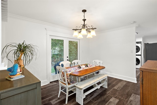 dining space featuring french doors, dark wood-type flooring, stacked washing maching and dryer, ornamental molding, and an inviting chandelier