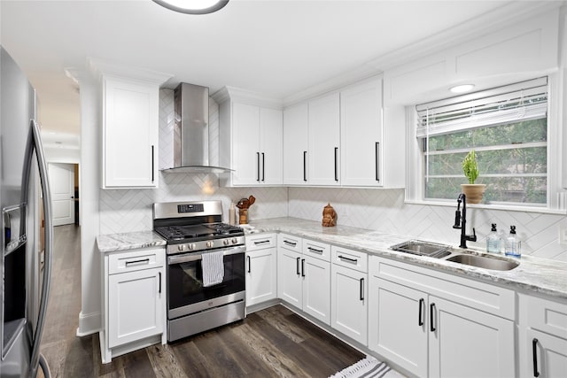 kitchen with wall chimney range hood, white cabinets, appliances with stainless steel finishes, and sink