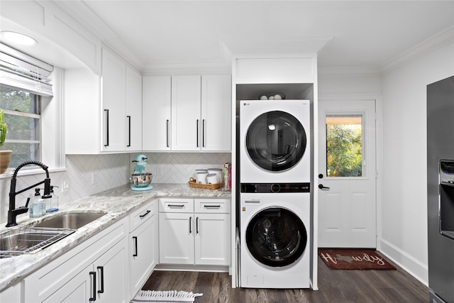 laundry room featuring dark wood-type flooring, sink, crown molding, and stacked washing maching and dryer