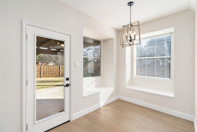 doorway to outside with an inviting chandelier and wood-type flooring