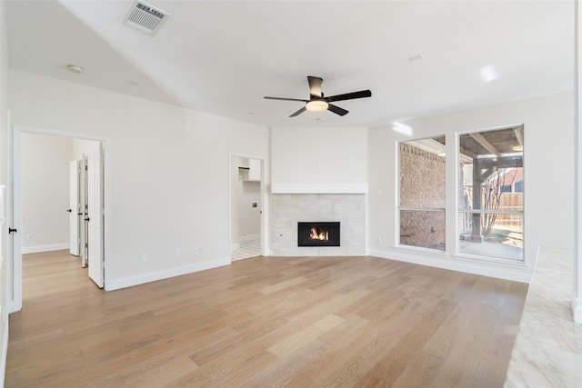 unfurnished living room featuring a tiled fireplace, ceiling fan, and light wood-type flooring