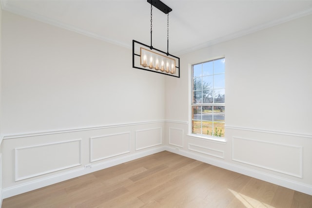 unfurnished dining area featuring wood-type flooring, an inviting chandelier, and crown molding