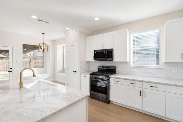 kitchen with pendant lighting, white cabinetry, sink, light stone countertops, and gas range oven