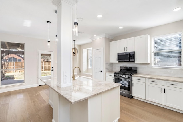 kitchen featuring sink, hanging light fixtures, stainless steel appliances, white cabinets, and a center island with sink