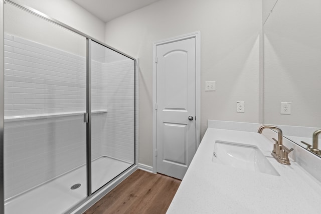 bathroom with wood-type flooring, a shower with door, and vanity