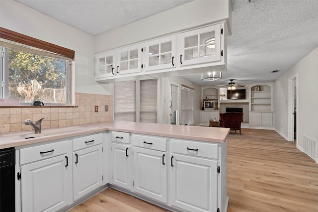 kitchen featuring tasteful backsplash, dishwasher, white cabinetry, sink, and kitchen peninsula