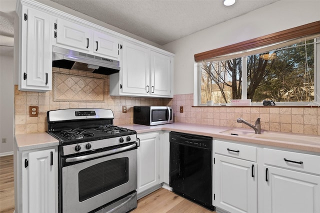 kitchen featuring white cabinetry, a textured ceiling, light hardwood / wood-style floors, decorative backsplash, and stainless steel appliances