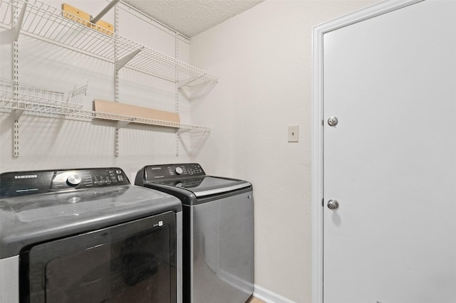 clothes washing area with independent washer and dryer and a textured ceiling