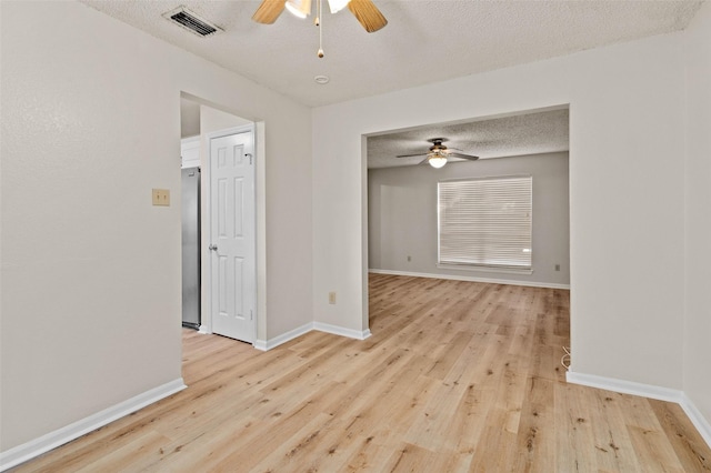 empty room featuring ceiling fan, light hardwood / wood-style floors, and a textured ceiling