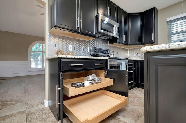 kitchen featuring light carpet, light stone countertops, decorative backsplash, and stainless steel appliances