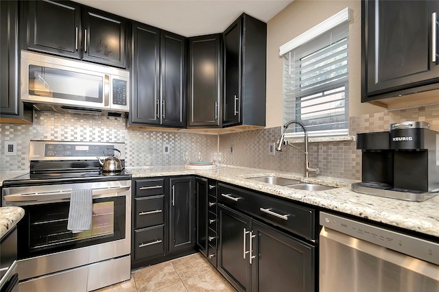 kitchen with sink, stainless steel appliances, and light stone countertops