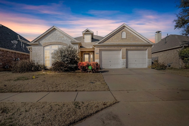 view of front of home with a garage, driveway, roof with shingles, and stone siding