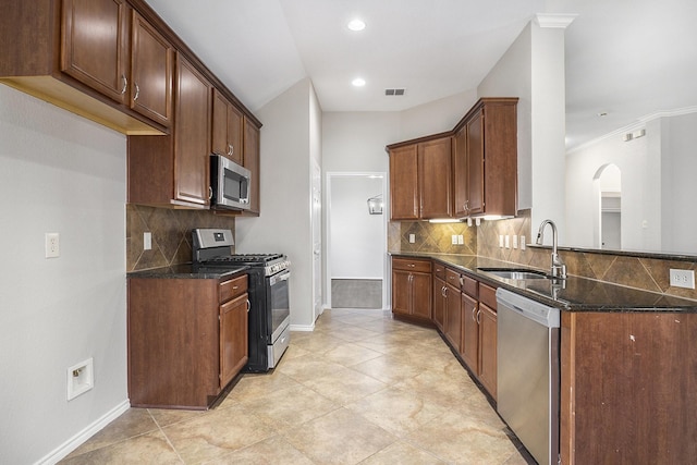 kitchen with appliances with stainless steel finishes, dark stone counters, visible vents, and a sink