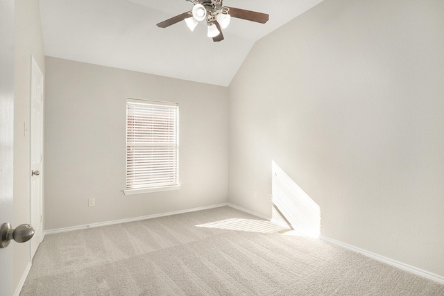 carpeted empty room with lofted ceiling, a ceiling fan, and baseboards