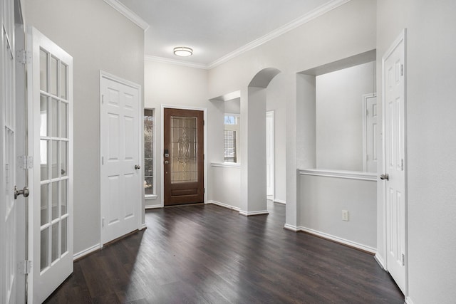 foyer with dark wood-style floors, arched walkways, ornamental molding, and baseboards