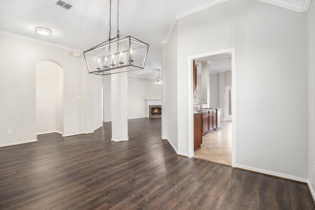 unfurnished dining area with arched walkways, visible vents, a lit fireplace, dark wood-style floors, and crown molding