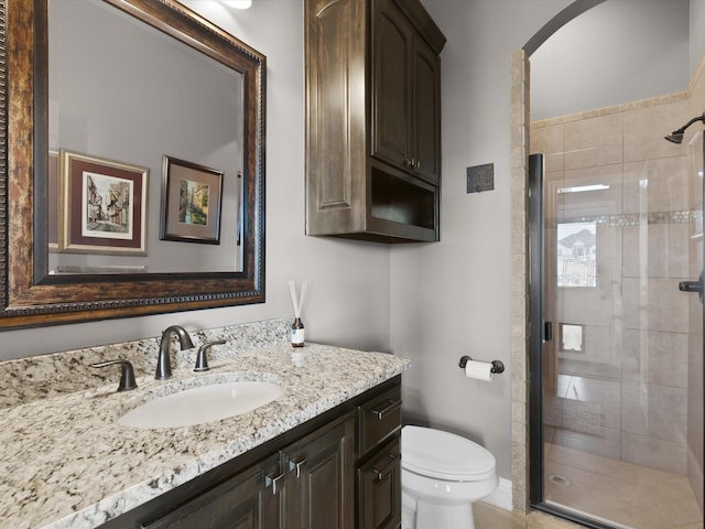 bathroom featuring a shower with door, vanity, and toilet