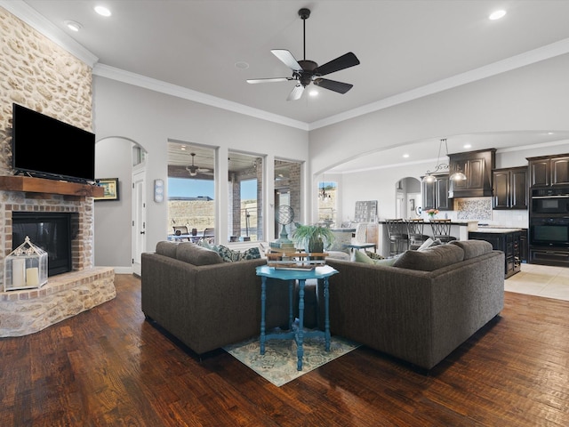 living room with hardwood / wood-style flooring, a fireplace, ornamental molding, and ceiling fan