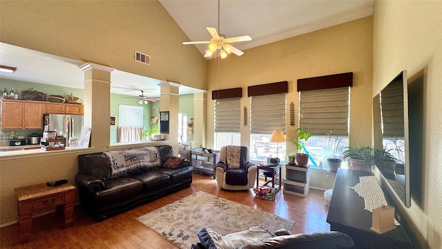 living room featuring hardwood / wood-style flooring, high vaulted ceiling, ceiling fan, and ornate columns