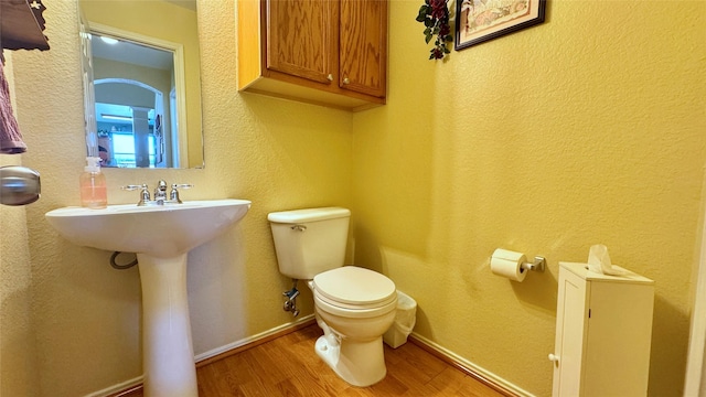 bathroom featuring wood-type flooring and toilet