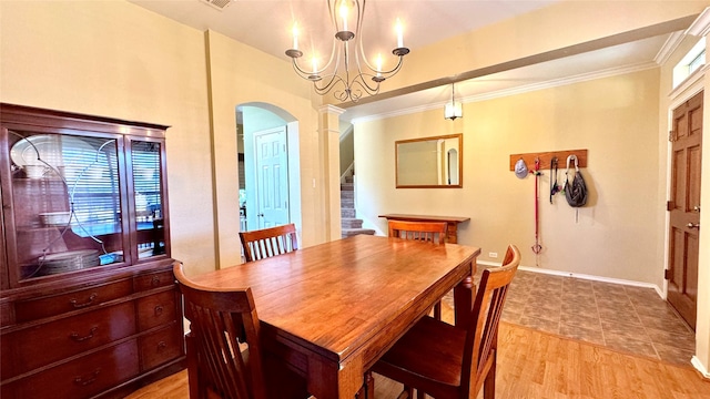 dining room with decorative columns, ornamental molding, and light wood-type flooring