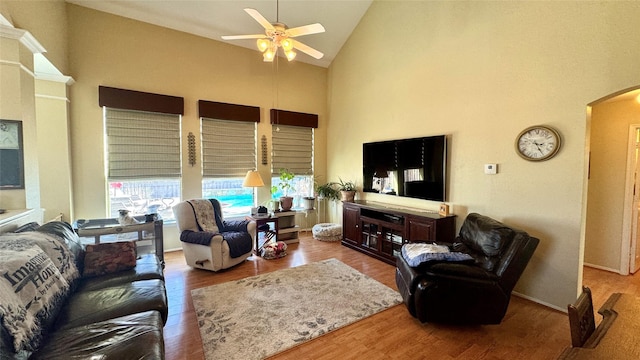 living room with light wood-type flooring, ceiling fan, and high vaulted ceiling