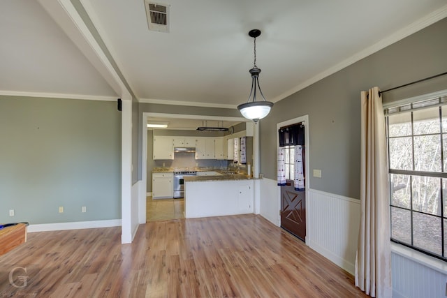 kitchen with kitchen peninsula, decorative light fixtures, light wood-type flooring, white cabinetry, and stainless steel range