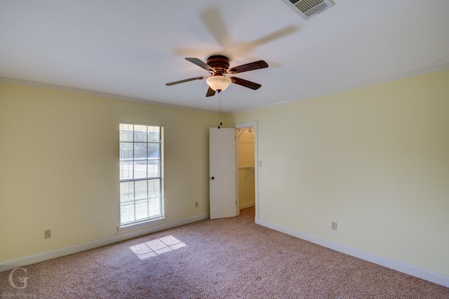 spare room with ceiling fan, crown molding, and light carpet