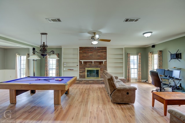 playroom featuring plenty of natural light, built in shelves, crown molding, and light wood-type flooring