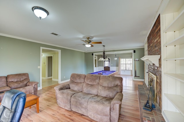 living room with light wood-type flooring, ornamental molding, a fireplace, and pool table