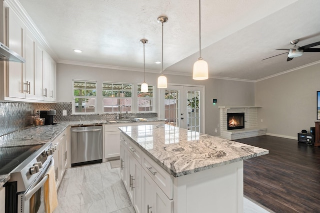 kitchen featuring white cabinetry, sink, a kitchen island, decorative light fixtures, and stainless steel appliances