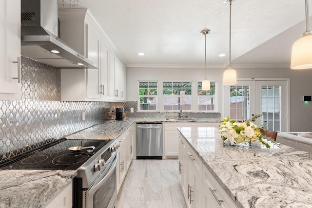 kitchen featuring wall chimney exhaust hood, white cabinets, decorative light fixtures, and stainless steel appliances