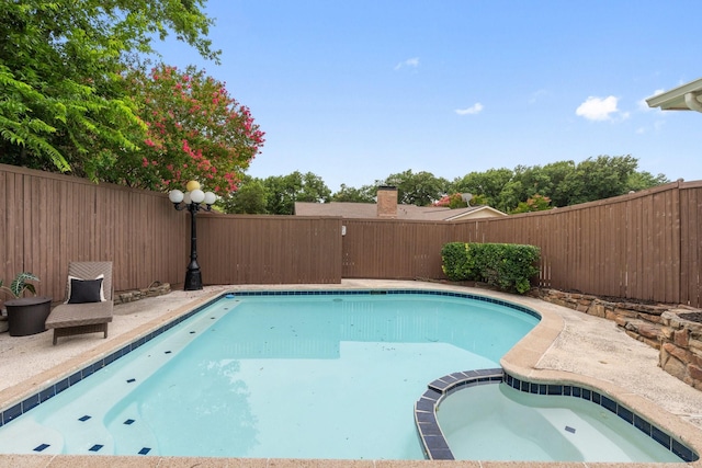 view of swimming pool with an in ground hot tub