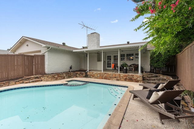 view of pool with an in ground hot tub, a patio area, and french doors