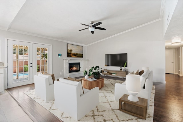 living room with a fireplace, light wood-type flooring, french doors, ornamental molding, and vaulted ceiling