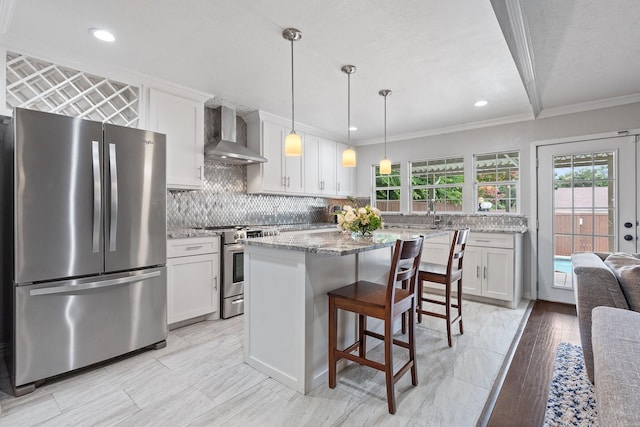 kitchen with crown molding, white cabinets, wall chimney range hood, and stainless steel appliances