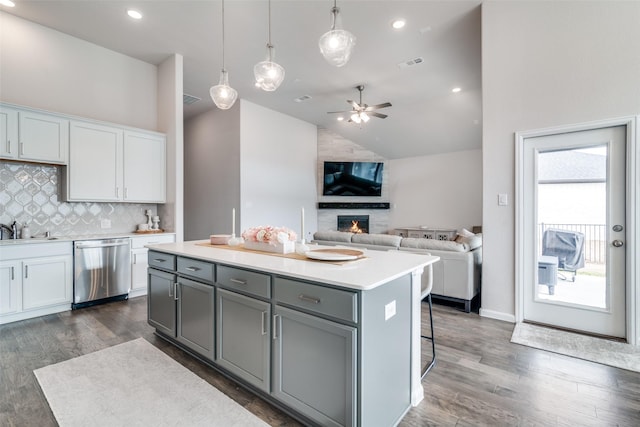 kitchen with sink, white cabinets, hanging light fixtures, a center island, and stainless steel dishwasher