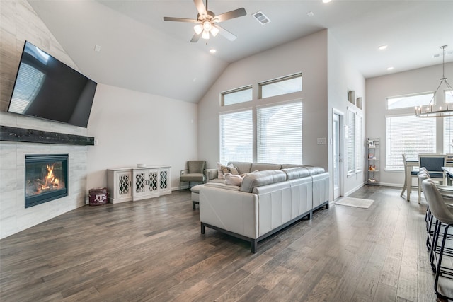 living room featuring vaulted ceiling, dark hardwood / wood-style floors, ceiling fan with notable chandelier, and a fireplace