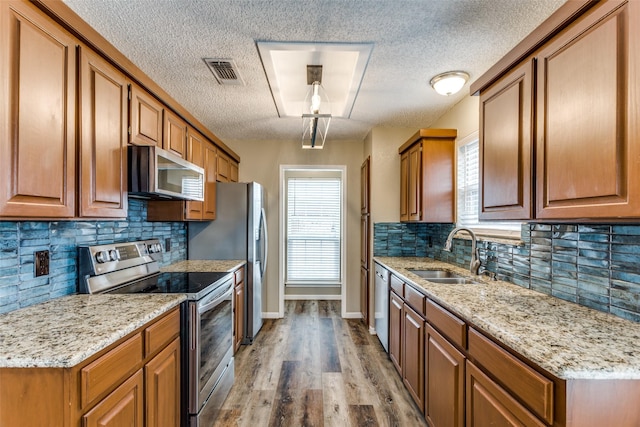 kitchen with sink, light wood-type flooring, plenty of natural light, and appliances with stainless steel finishes