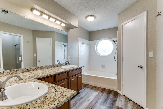 bathroom featuring vanity, tiled shower / bath, hardwood / wood-style floors, and a textured ceiling