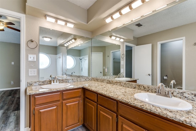 bathroom featuring ceiling fan, vanity, hardwood / wood-style floors, and a textured ceiling