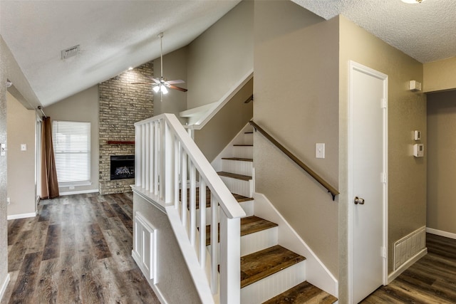 staircase featuring ceiling fan, hardwood / wood-style flooring, a fireplace, and a textured ceiling