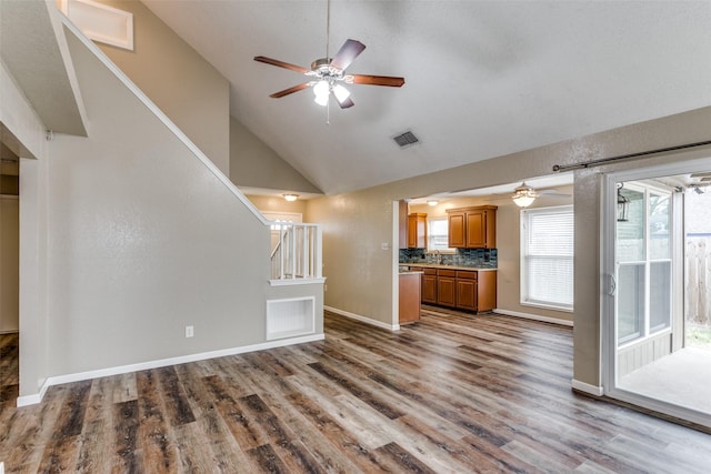 unfurnished living room with hardwood / wood-style flooring, high vaulted ceiling, and ceiling fan