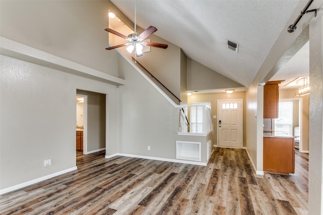 foyer with ceiling fan, dark hardwood / wood-style flooring, high vaulted ceiling, and a textured ceiling