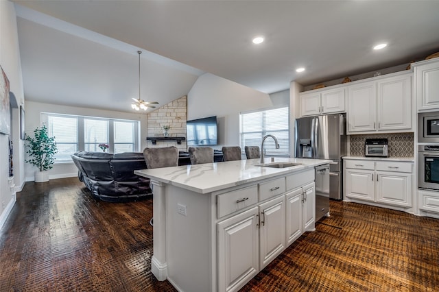 kitchen featuring white cabinetry, sink, backsplash, vaulted ceiling, and a center island with sink