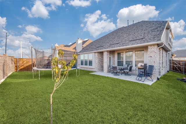 back of property featuring a trampoline, a lawn, and a patio area