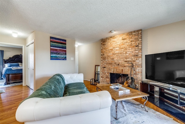 living room with a fireplace, light hardwood / wood-style floors, and a textured ceiling