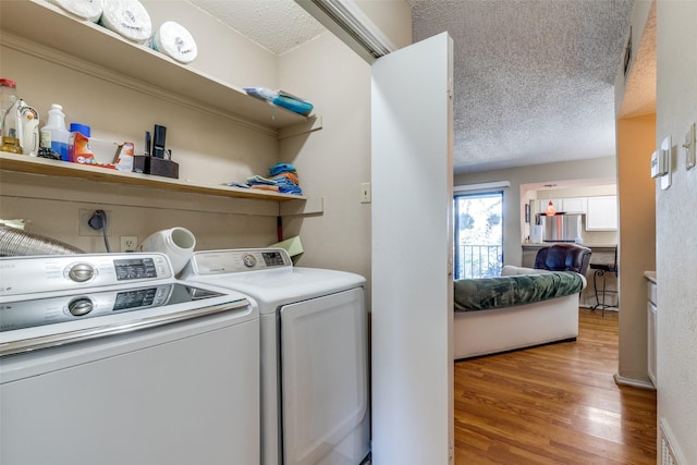 laundry room featuring a textured ceiling, laundry area, visible vents, independent washer and dryer, and light wood finished floors