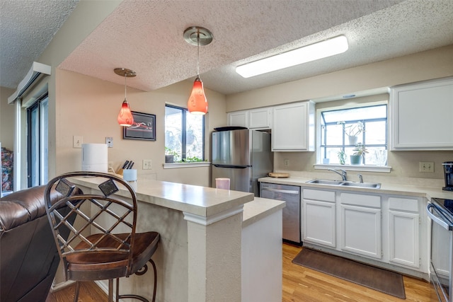 kitchen featuring a kitchen bar, sink, white cabinetry, pendant lighting, and stainless steel appliances