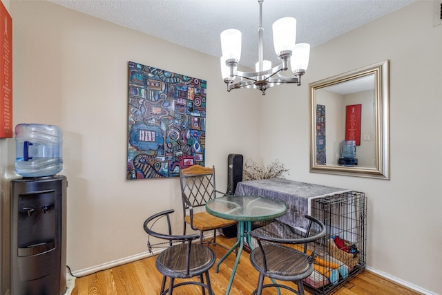 dining room featuring an inviting chandelier, a textured ceiling, baseboards, and wood finished floors